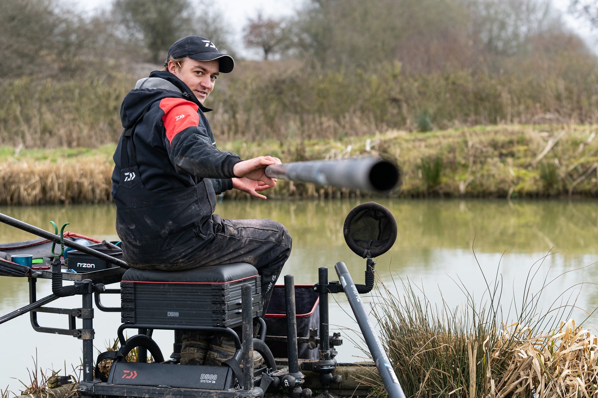 Рибар на платформа DAIWA D500SB - D36, готов за улов в естествени условия при водоем.