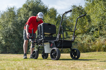 Човек настройва количка за багаж Daiwa DAIWA FOLD N GO MATCH BARROW на открито в природата.