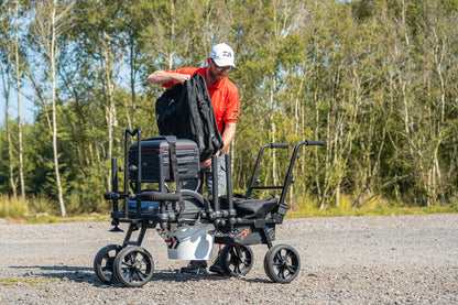 Количка за багаж Daiwa DAIWA FOLD N GO MATCH BARROW с рибарски такъми на фона на природа.