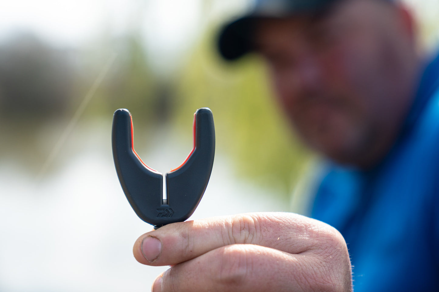 Преден държач за въдица DAIWA N'ZON COMPACT FRONT ROD REST, показан от рибар на водоем.