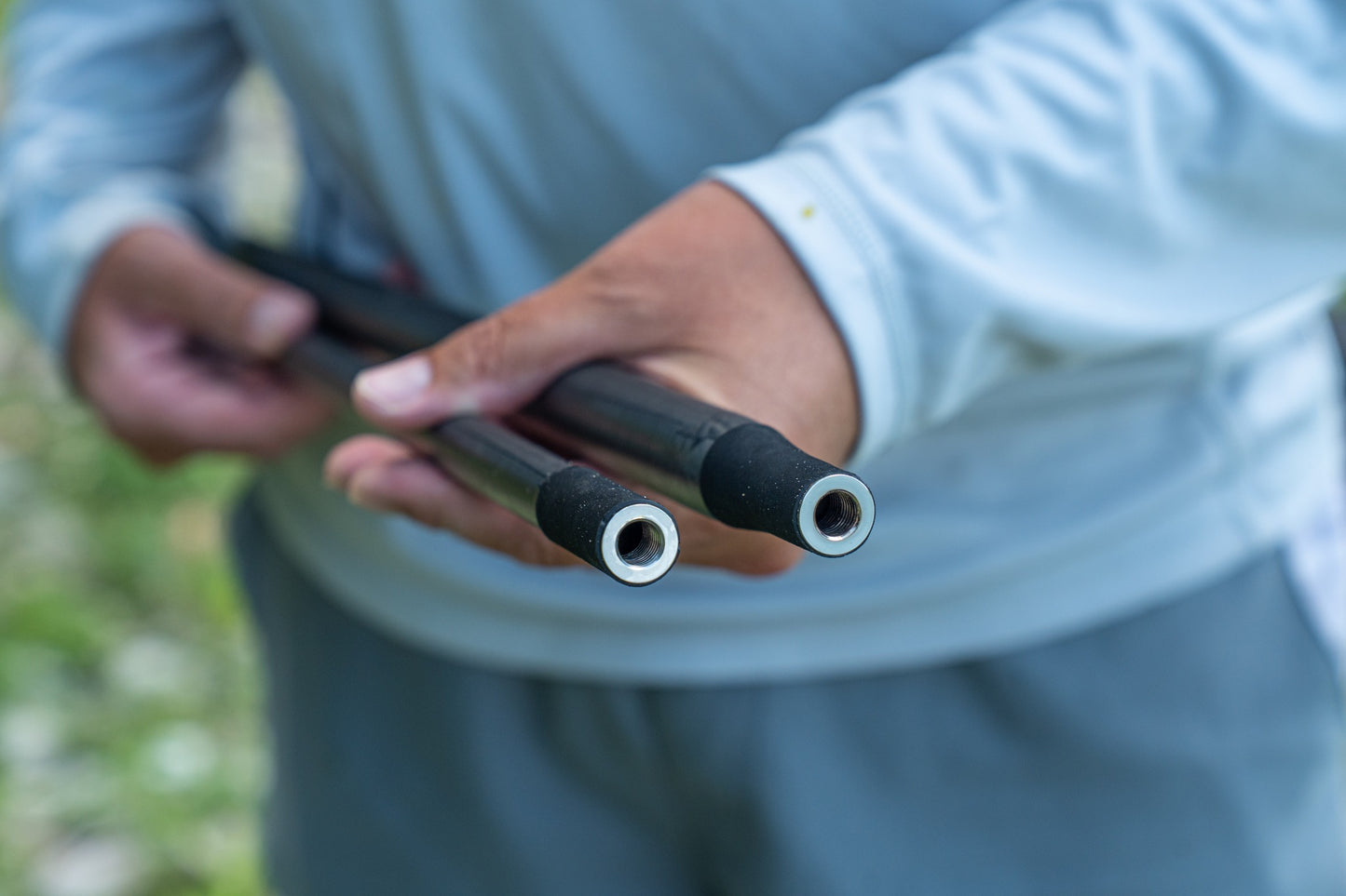 Дръжка за кеп DAIWA 25 AIR LANDING NET HANDLE 4.50m в ръцете на рибар, готова за употреба.