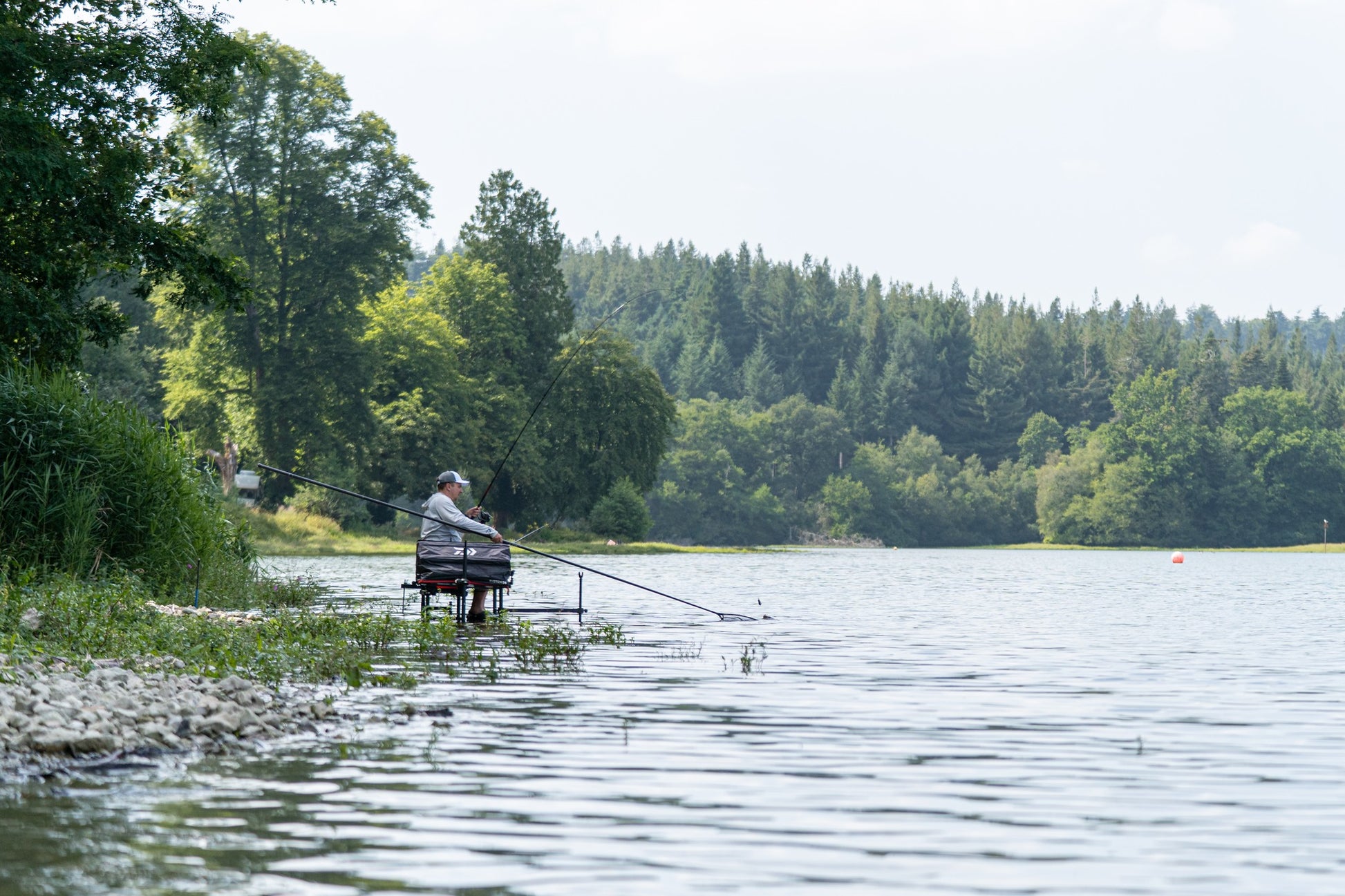Дръжка за кеп DAIWA 25 AIR LANDING NET HANDLE 4.50m - риболовец на брега на водоем, риболовна сесия на природа.