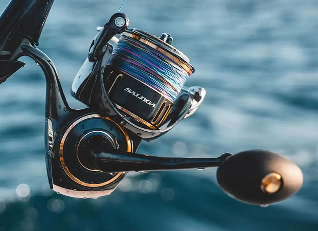 Макара за морски риболов DAIWA 25 SALTIGA G, риболовен аксесоар с цветен влакно на фона на морска вода.