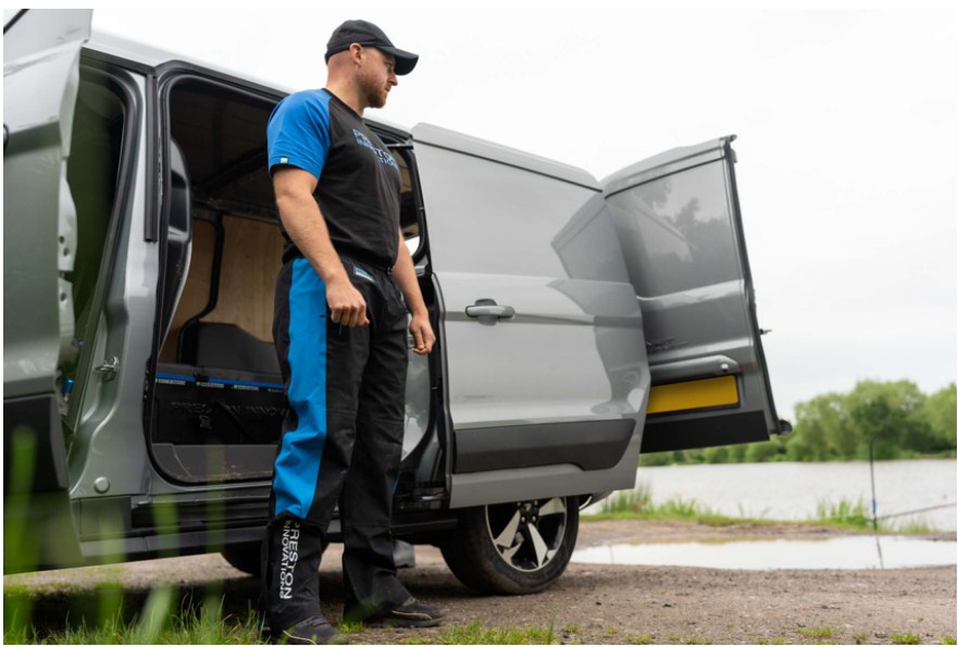 Мъж в водоустойчив панталон PRESTON DF ULTRA TROUSERS стои до отворена врата на ван край водоем.