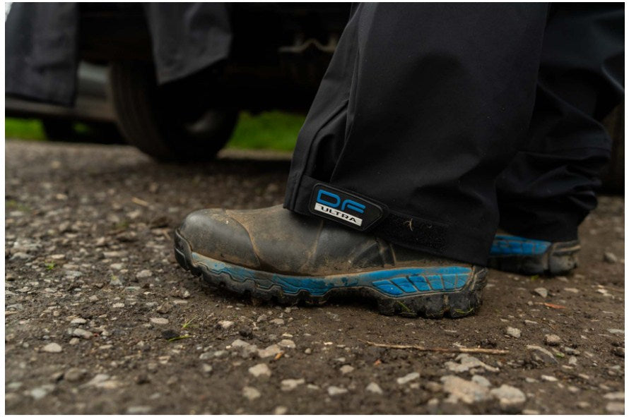 Водоустойчив панталон PRESTON DF ULTRA TROUSERS с удобни обувки на неравен терен при риболов.