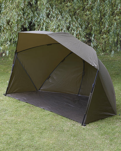 Броли DAIWA 23 MISSION BROLLY на естествен пасище, идеален за риболов и почивка на открито.