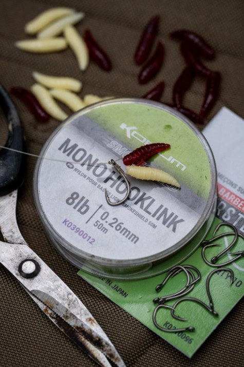 Изкуствени плуващи бели червеи Korum FLOATING GRUBS - IMITATION MAGGOTS и риболовни аксесоари на работна повърхност.