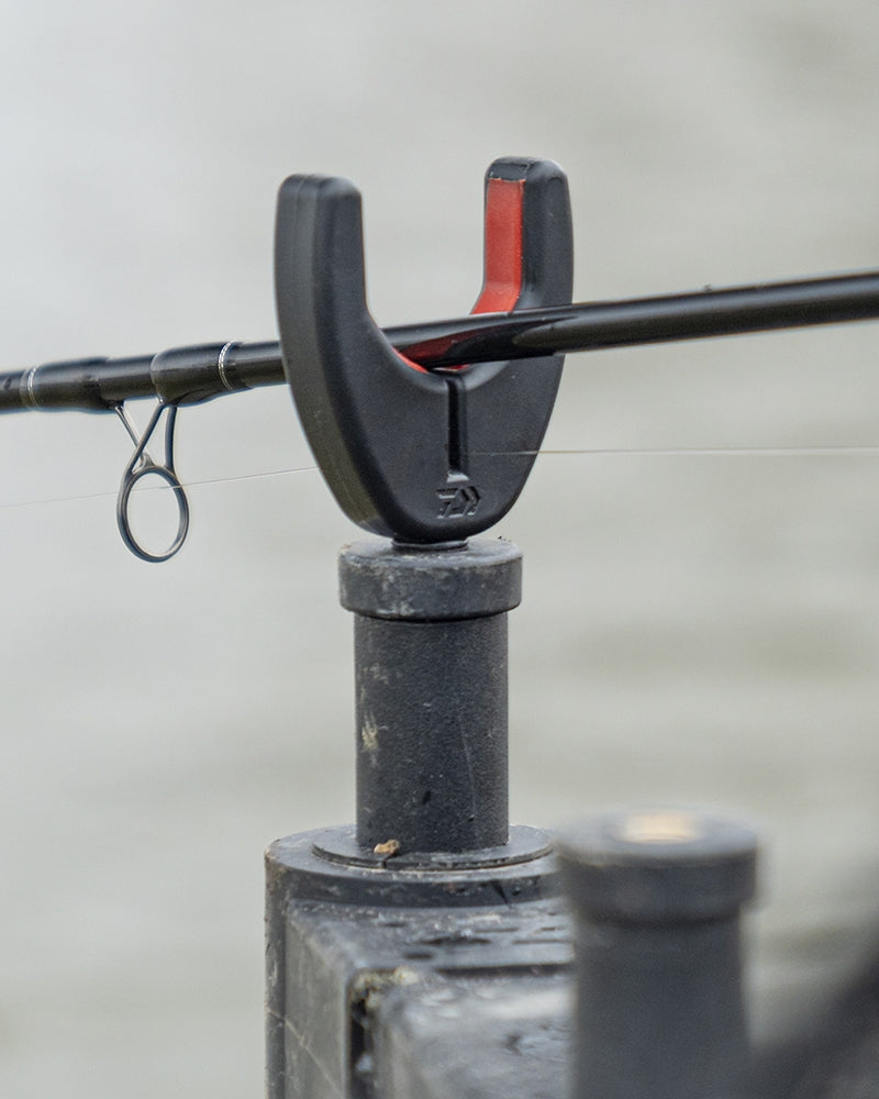 Преден държач за въдица DAIWA N'ZON COMPACT FRONT ROD REST с черен и червен дизайн, удержаващ въдицата при риболов.