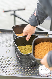 Кутия за стръв DAIWA NZON STACKING EVA BAIT BOX - 4 PINT с различни примамки на риболовна платформа.