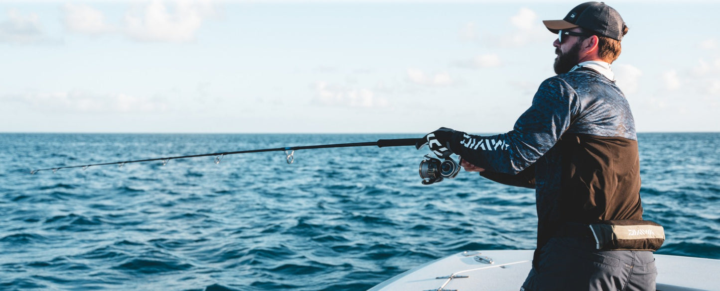 Мъж риболов на лодка с макара за морски риболов DAIWA 25 SALTIGA G на фона на морската повърхност.